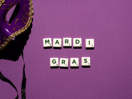 Colorful Mardi Gras arrangement with tiles spelling 'Mardi Gras' and a decorative mask on a purple backdrop.