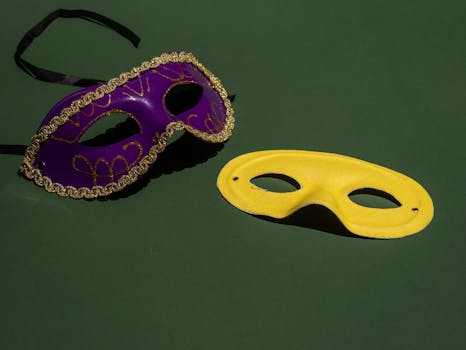 Purple and yellow masquerade masks on a green background, perfect for festive themes.