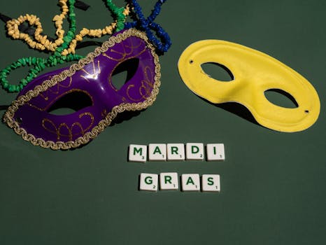 Vibrant Mardi Gras masks and beads on a green background with Scrabble tiles spelling 'Mardi Gras'.