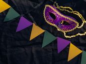 Colorful Mardi Gras mask and pennants on black fabric capturing festive spirit.