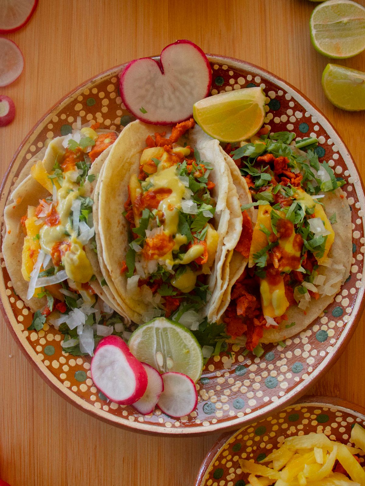 Colorful Mexican tacos topped with fresh cilantro, lime, and radish slices.