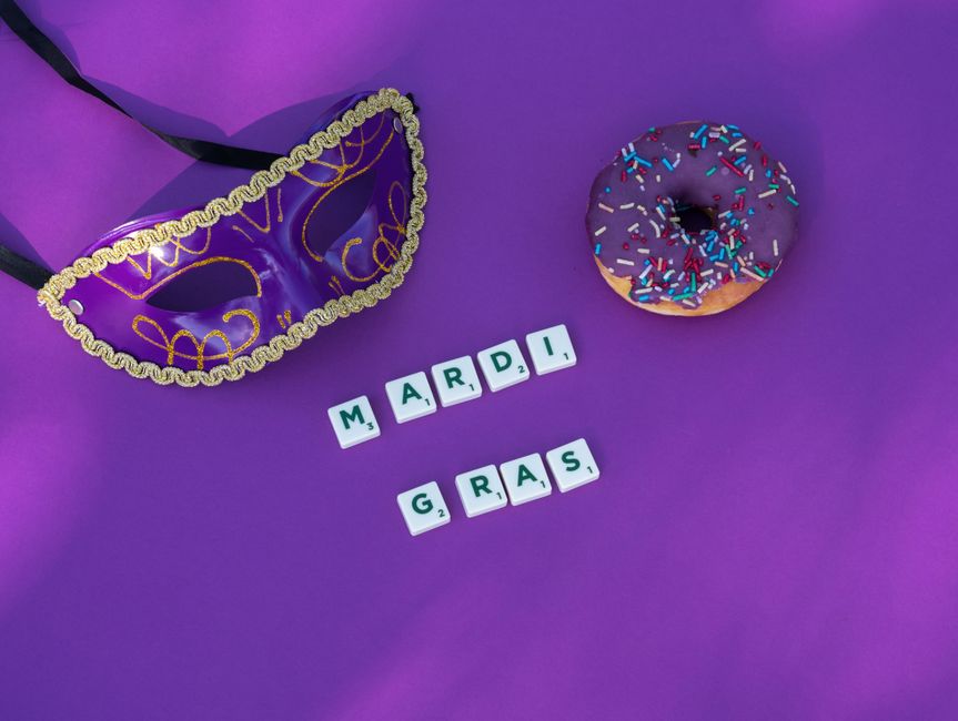 Colorful Mardi Gras theme featuring a purple mask, donut with sprinkles, and Scrabble tiles on a vibrant backdrop.