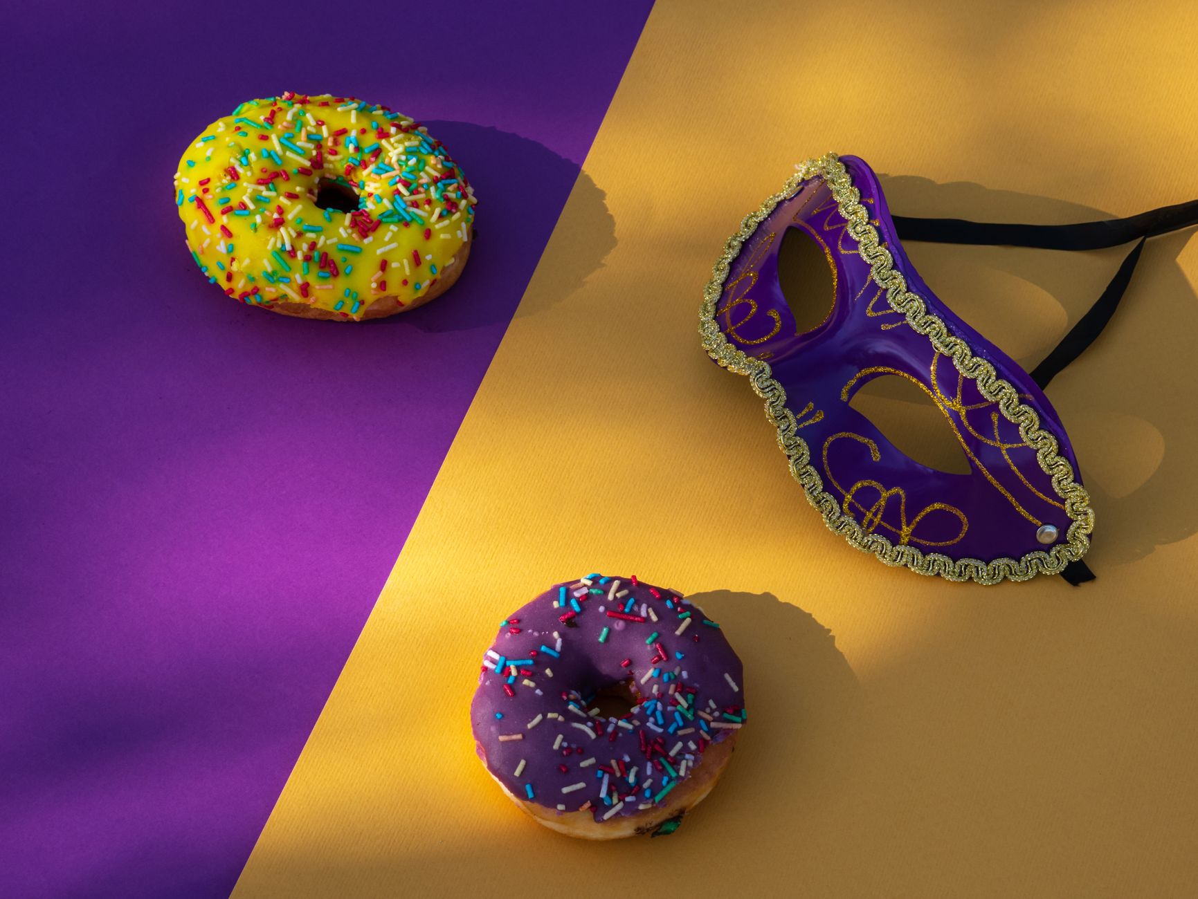 Cup of coffee alongside a jelly-filled Bismark donut on a rustic table setting