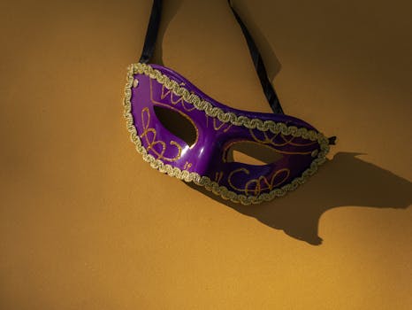 Purple masquerade mask with intricate golden design on a bright yellow surface.