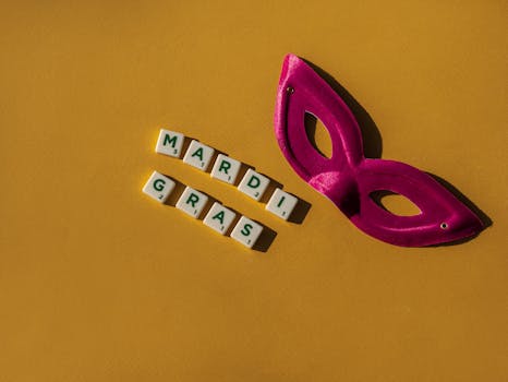 A bright purple mask and 'Mardi Gras' tiles on a yellow background, celebrating Mardi Gras festival.
