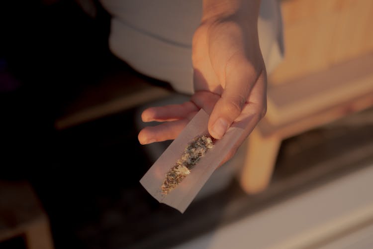 Person Holding A Rolling Paper With Marijuana