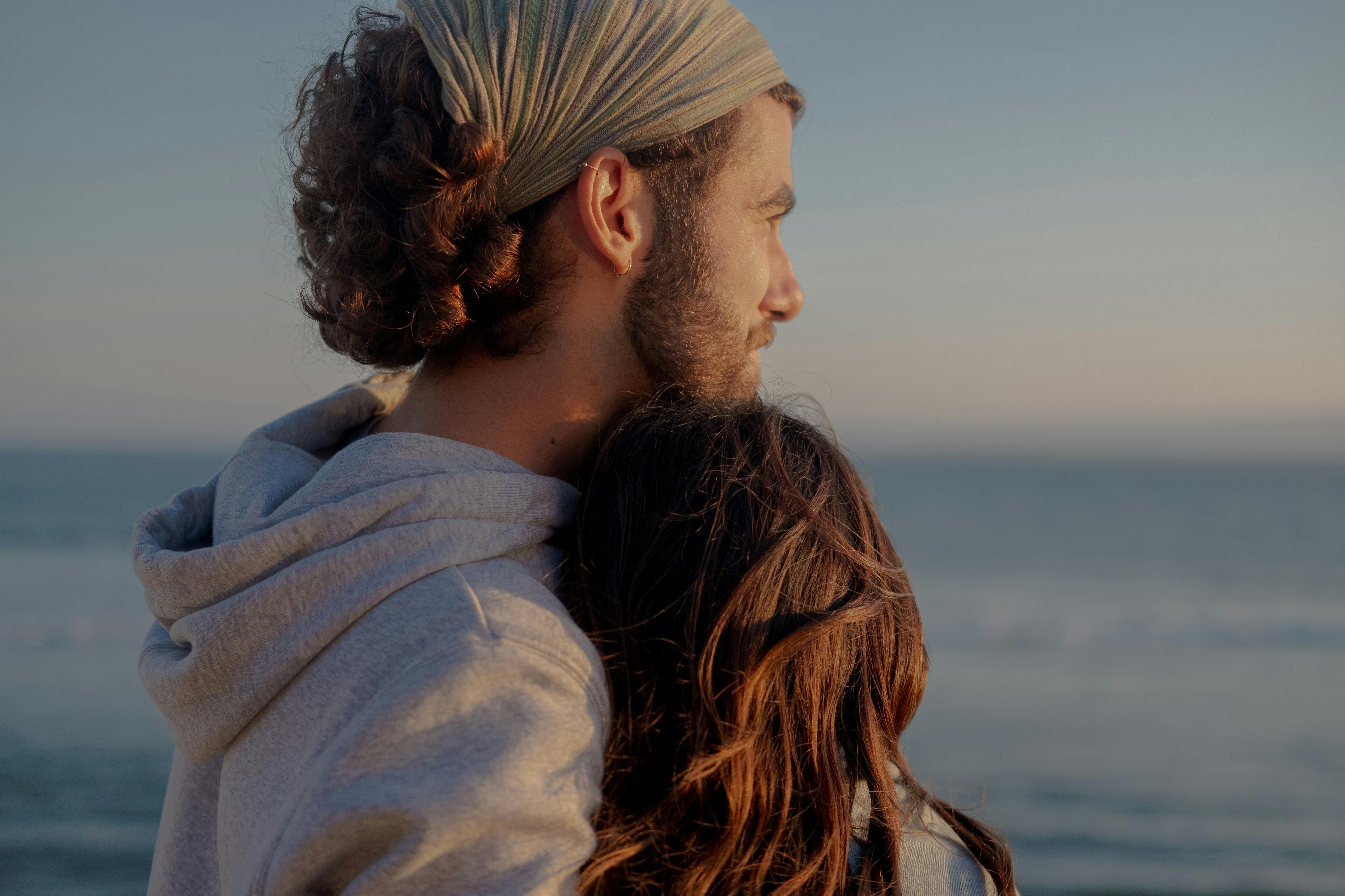 一对情侣在海边深情拥抱，在浪漫的环境中一起享受宁静的日落