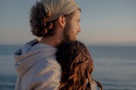 一对情侣在海边深情拥抱，在浪漫的环境中一起享受宁静的日落