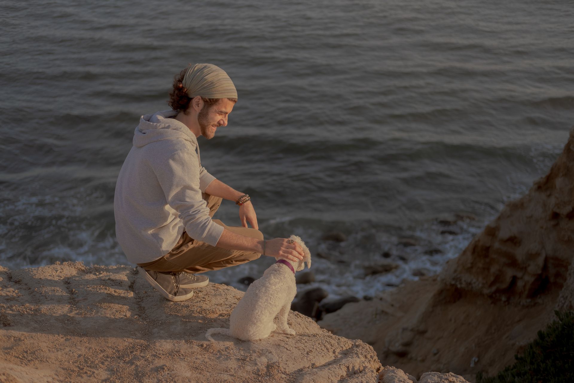 Man and His Pet Sitting Beside a Cliff