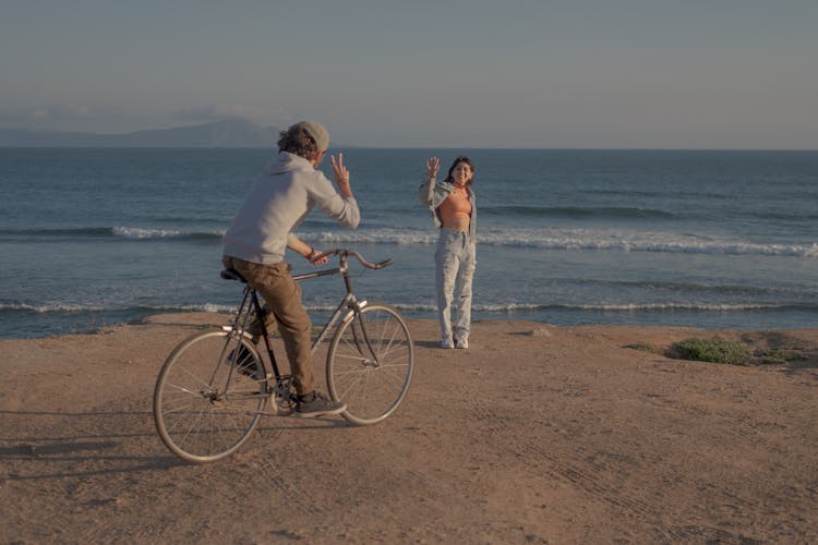 A Man And Woman On The Beach With Bicycle 