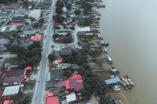 Free Drone view of Chukai town by the Terengganu river, showcasing local architecture and moored boats. Stock Photo