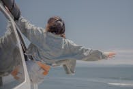 一名女子从车窗外探出来享受海风的背影