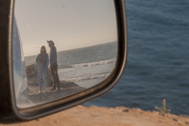 View Of A Man And Woman Reflecting On The Side Mirror