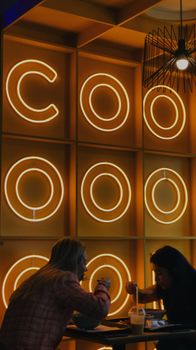 Atmospheric scene of two women dining in a neon-lit setting. Perfect for lifestyle imagery.