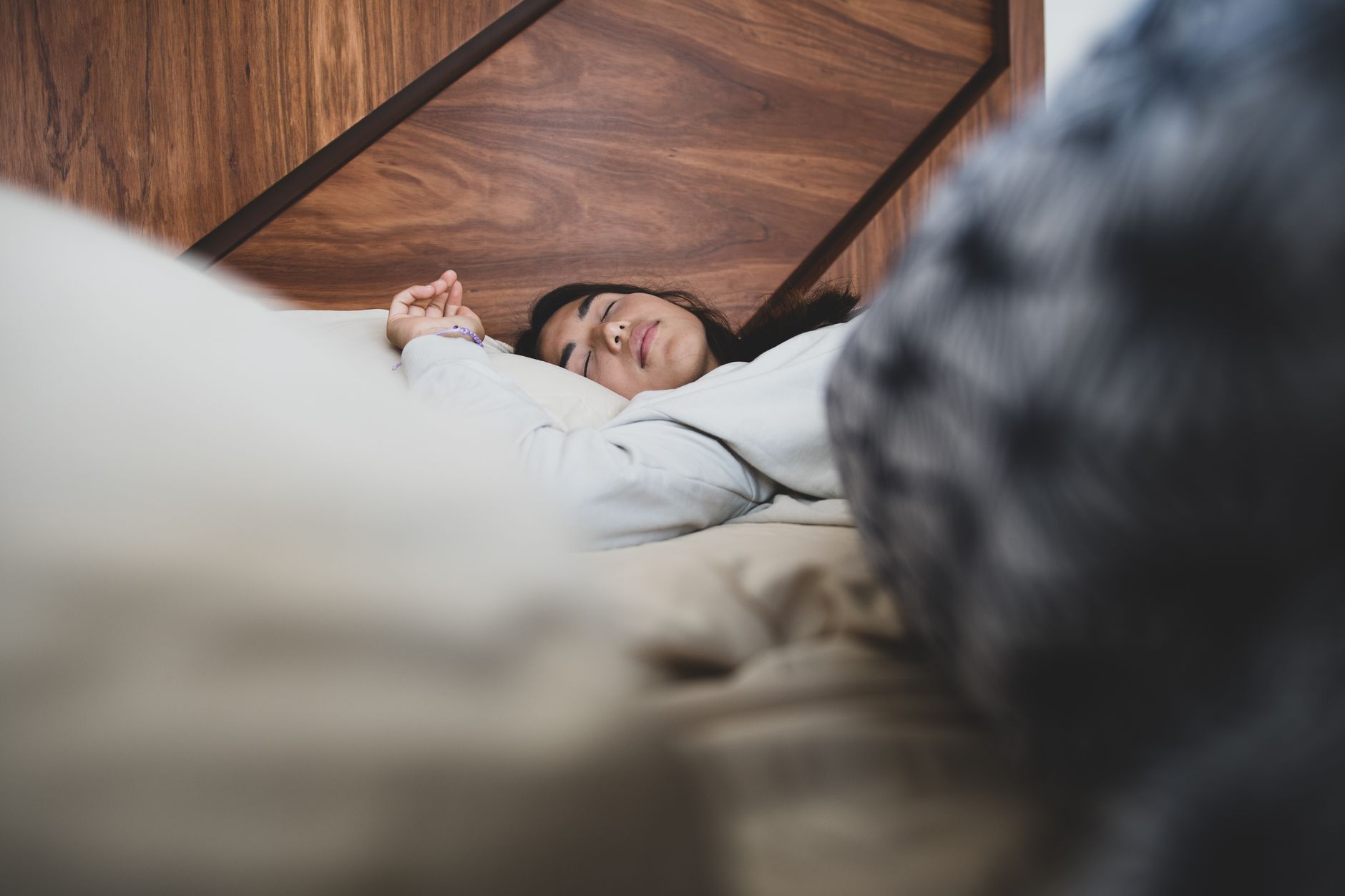 A woman peacefully sleeping on a bed with soft linens, practicing healthy sleep hygiene.