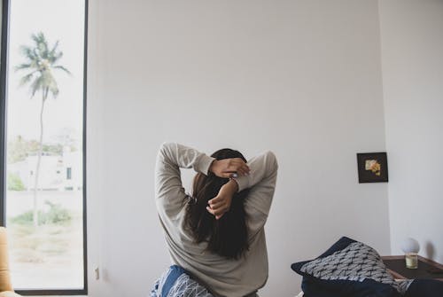 Free A Back View of a Woman in Gray Sweater Stretching Her Arms in the Morning Stock Photo