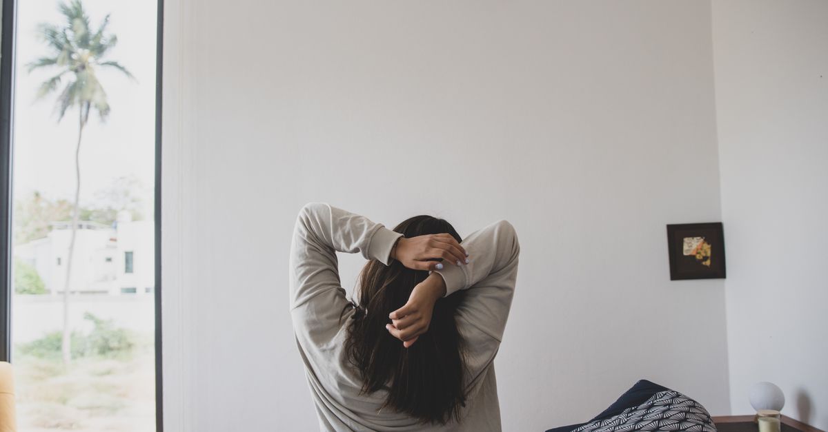 person doing morning stretches by a window, natural light, simple routine