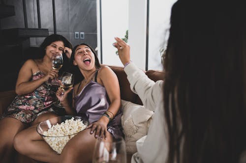 Women Sitting on the Couch while Holding Wine Glasses