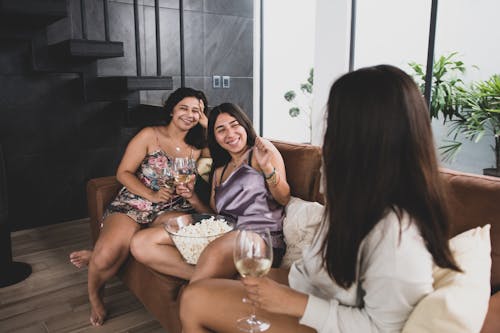 A Group of Friends Sitting on the Couch Having Fun while Holding Wine Glasses
