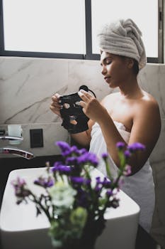 Young woman applying a facial mask in a luxurious bathroom for self-care.