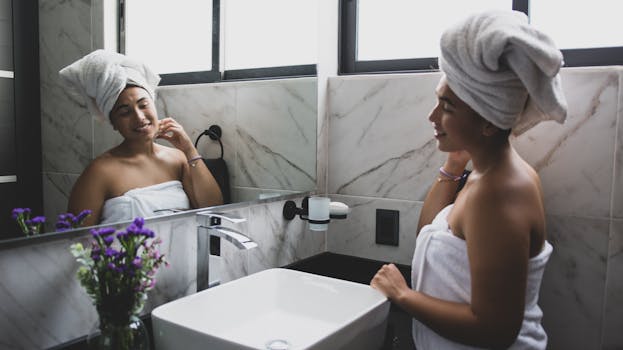 A woman enjoying her morning skincare routine with a towel wrap in a stylish bathroom.