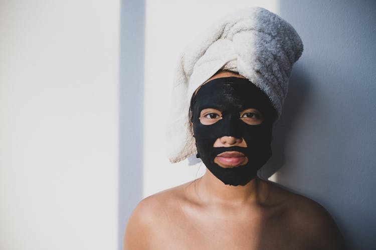 Woman In Black Facial Mask And Wrapped Head In Towel