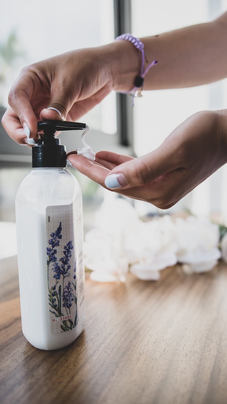 A Woman Squeezing A Lotion Pump Bottle