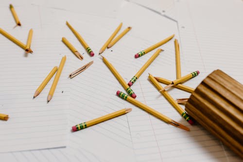 Free Broken Wooden Pencils on Top of Blank Sheets of Paper Stock Photo