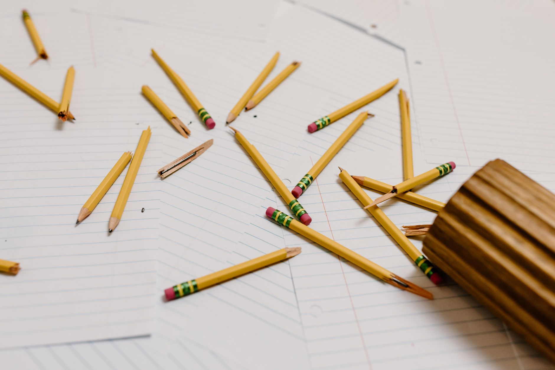 Scattered broken pencils on papers depict workplace stress or burnout.