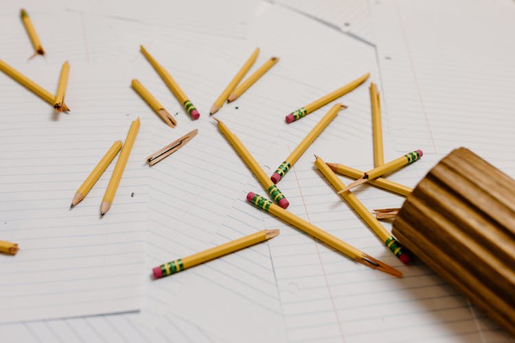 Broken Wooden Pencils On Top Of Blank Sheets Of Paper