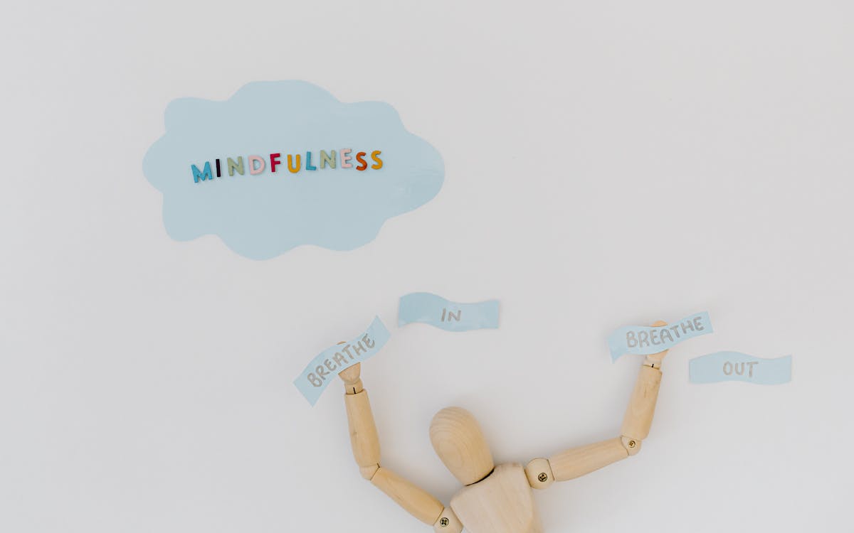 Wooden mannequin with 'Mindfulness' and 'Breathe In Out' text on a minimalistic background.