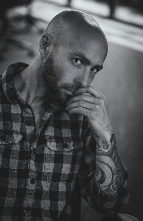 Monochrome Photo of a Man with an Arm Tattoo Posing with His Hand on His Mouth