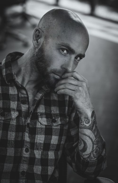 Free Dramatic grayscale portrait of a bearded man with tattoos, deep in thought. Stock Photo