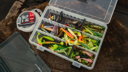 Free A top view of colorful fishing lures in an organized plastic box on a wooden surface outdoors. Stock Photo