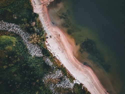 Free Stunning aerial photograph showcasing a vibrant coastline with lush trees, rocks, and gentle waves. Stock Photo