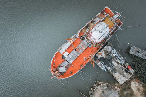 Free Aerial view of an orange ship docked in a harbor, showcasing industrial maritime activity. Stock Photo