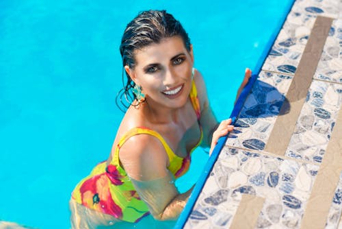 Photo of a Woman Wearing a Yellow and Purple Swimsuit in a Swimming Pool