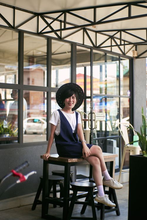 Free Stylish young woman wearing a fashionable hat and sitting at an outdoor cafe. Stock Photo