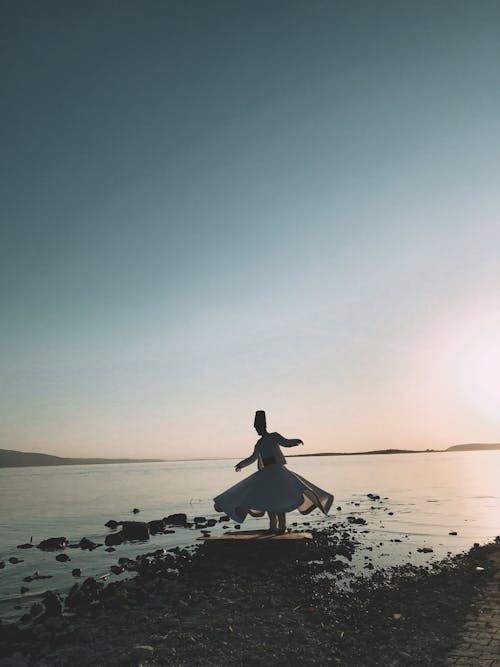 Man in Traditional Clothes Standing on Rock in Front of Sea