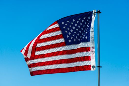 American flag billowing in the breeze against a vivid blue sky, symbolizing national pride.