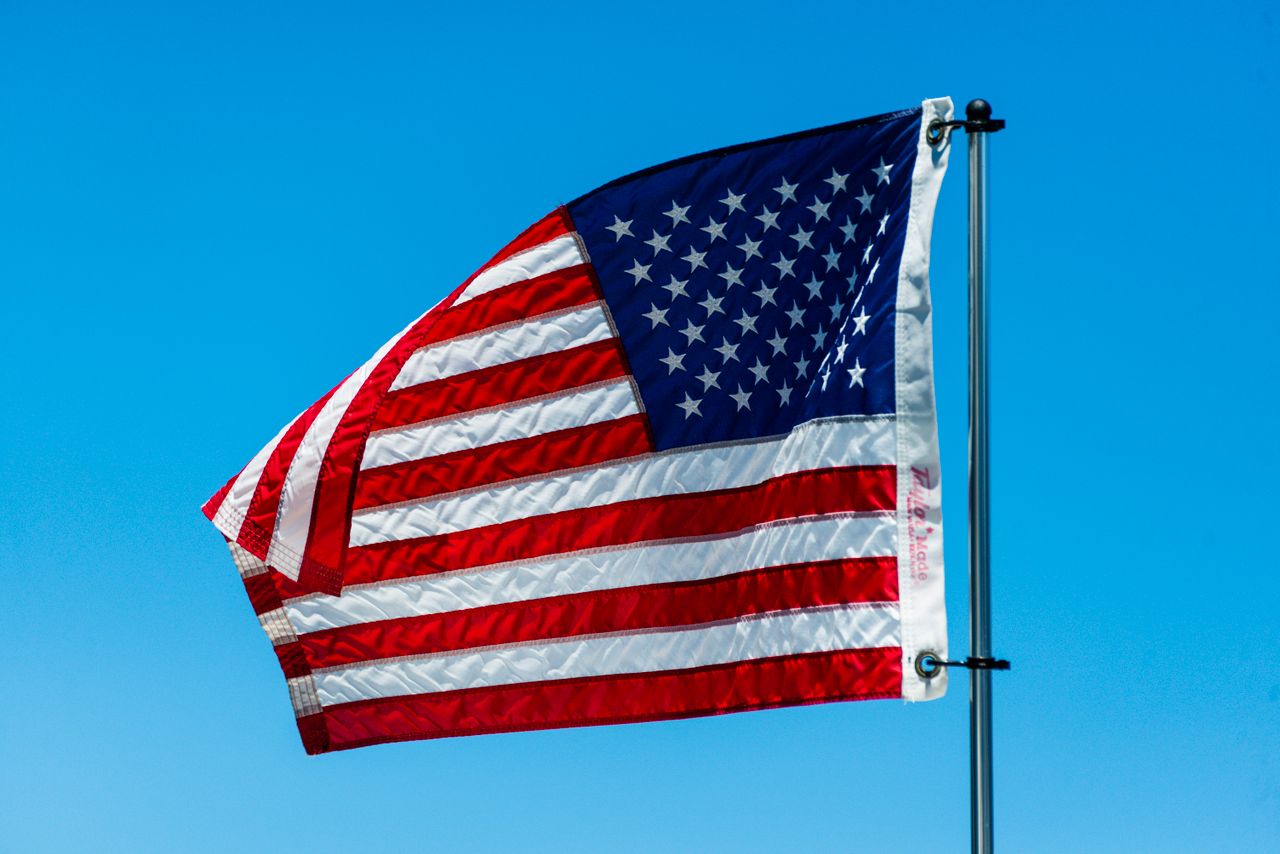 american flag billowing in the breeze against a vivid blue sky symboli