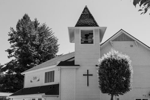 Free A black and white image of a church with a prominent bell tower and surrounding trees. Stock Photo