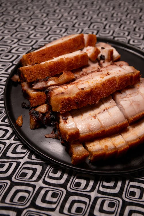 Close-Up Photo of a Black Plate with Crispy Roasted Pork