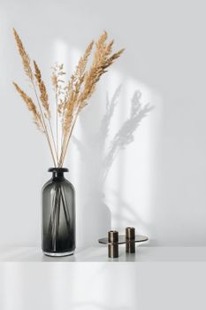Elegant minimalist decor featuring dried plants in a glass vase with soft lighting.