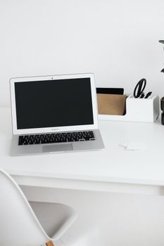 Simple modern workspace with a laptop, white desk, and office supplies in a minimalist style.