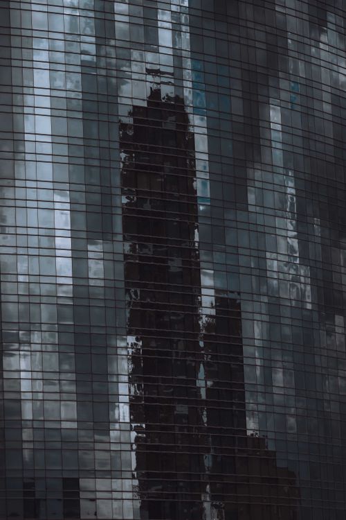 Free Reflective glass of an urban skyscraper captures the city skyline, creating a dramatic architectural scene. Stock Photo