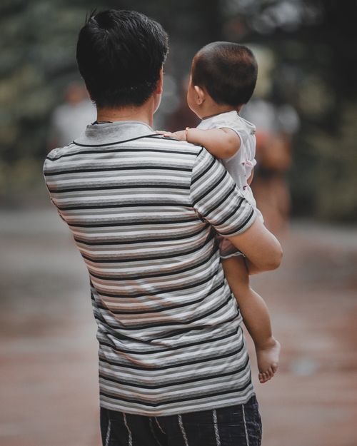 Free Father carrying his child outdoors, showcasing a loving and tender moment. Stock Photo