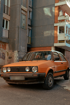 Classic VW car parked in a gritty urban environment with graffiti.