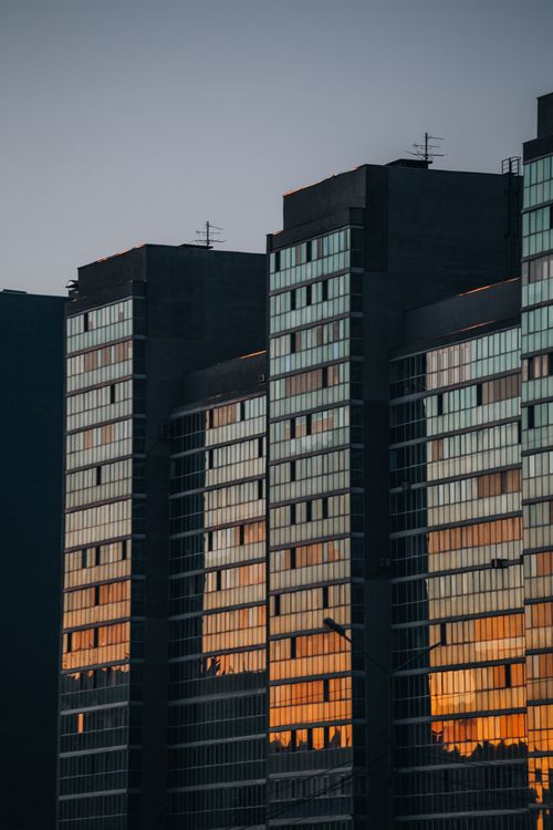 Free Sunset reflecting on the glass facade of modern high-rise buildings in a downtown area. Stock Photo