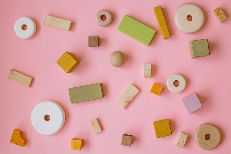 Pastel wooden blocks scattered on a pink background